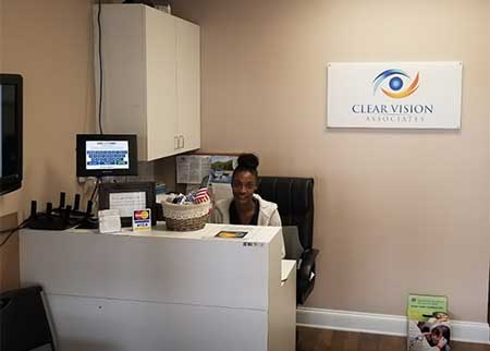 The image shows an individual seated at a desk inside an office space with a sign for  Clear Vision.