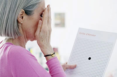 The image shows an elderly woman with her hand covering her face, seemingly distressed or upset, holding a piece of paper with a grid pattern and text on it.